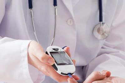 Doctor testing blood sugar with a glucometer.