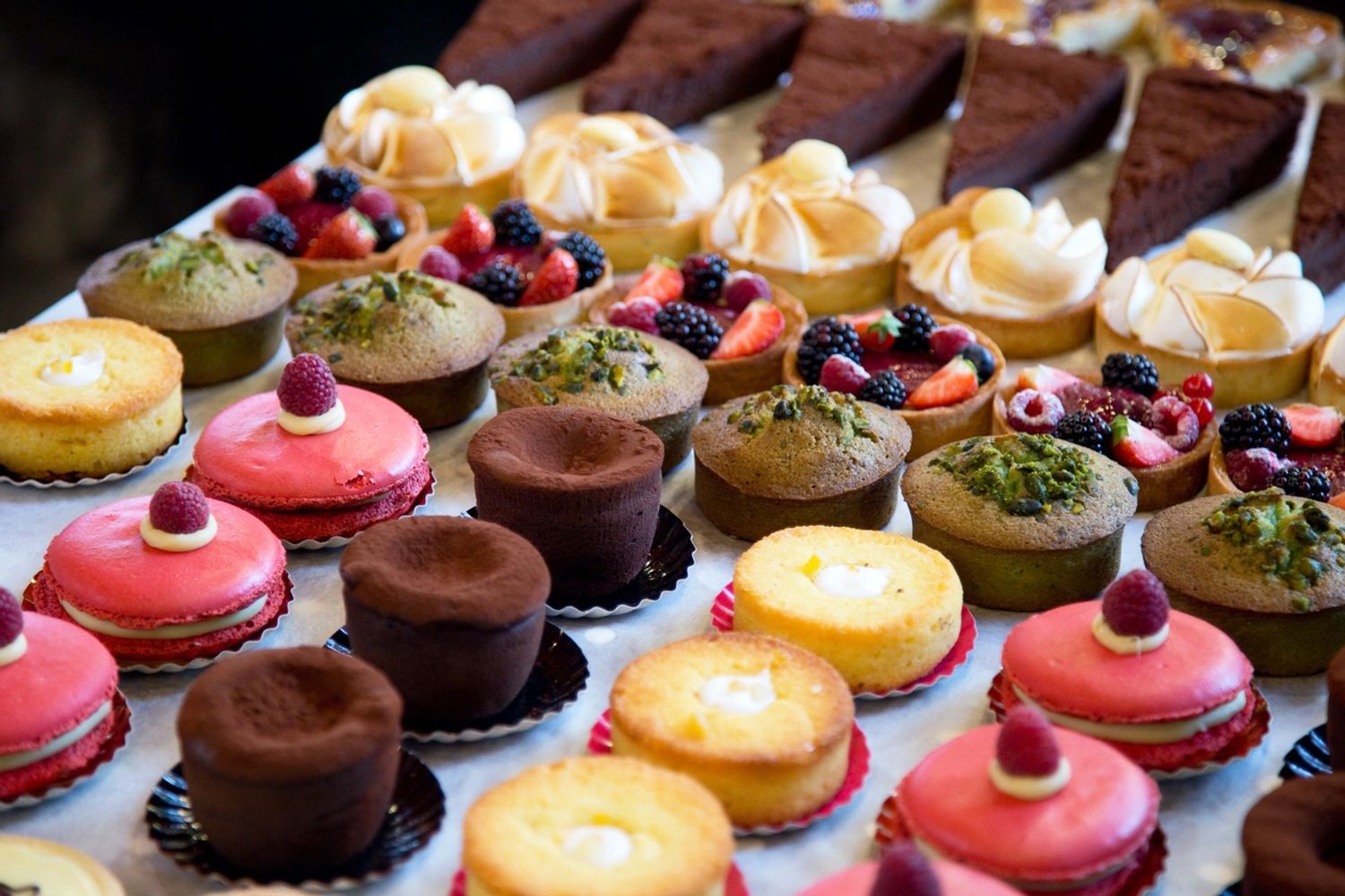 Assorted colorful gourmet pastries and desserts arranged on a table.
