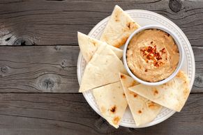 Plate of pita bread triangles with a bowl of seasoned dip.