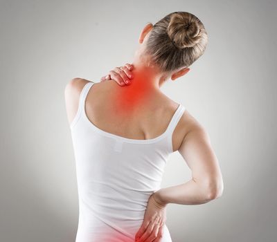 Illustration of neck and lower back pain showing a person holding sore areas highlighted in red.