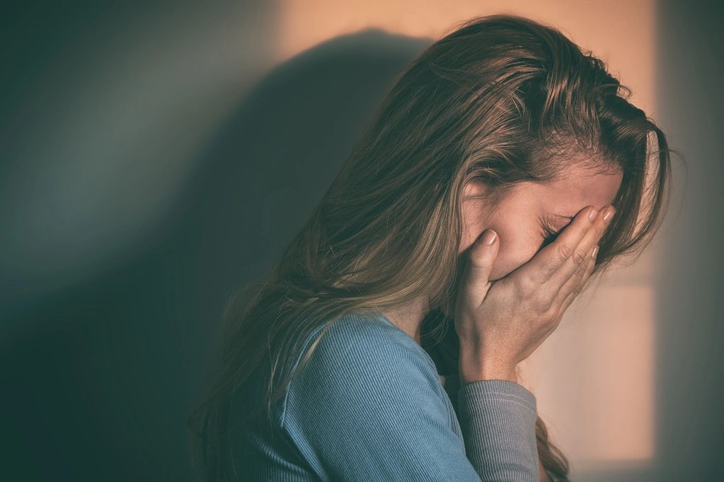A woman covering her face, appearing upset or distressed.