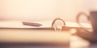 Close-up of a pen and an open binder on a desk with warm lighting.