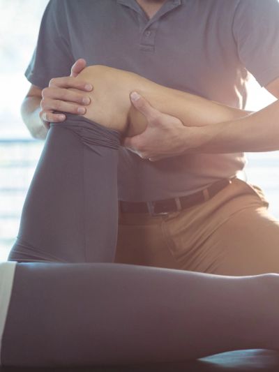 Physical therapist assisting patient with knee exercise during rehabilitation.