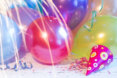 Colorful balloons and a decorated party hat on a festive surface.