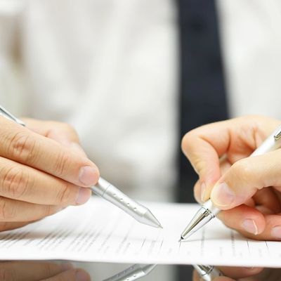 Two hands holding pens over a document.