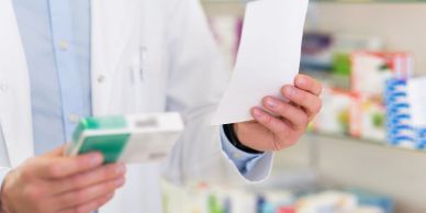 Pharmacist holding medication and prescription in a pharmacy.