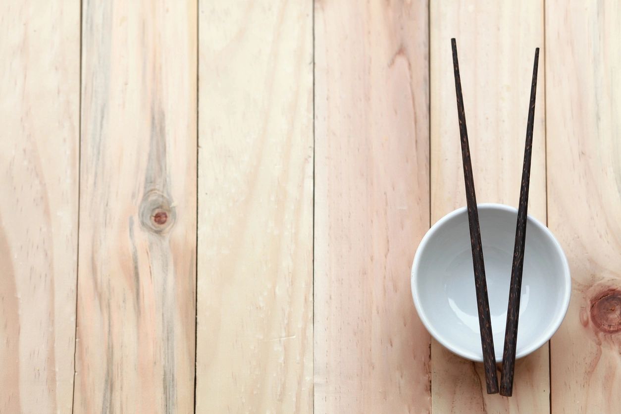 a white bowl with chopsticks on a wooden table