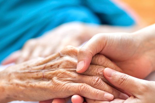 Young hands gently holding elderly hands in a comforting gesture.