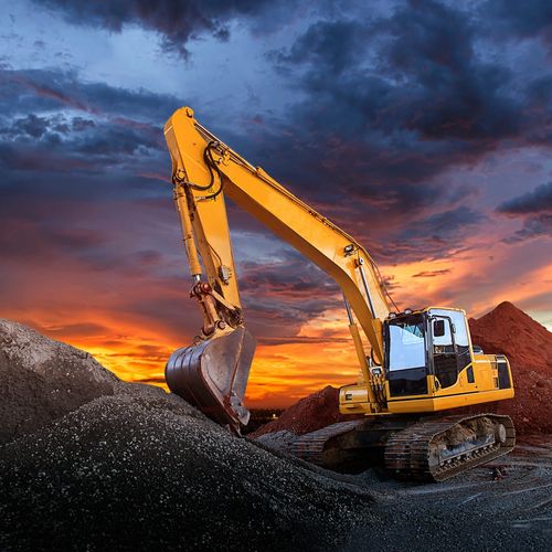 Excavator digging dirt in front of beautiful sunset