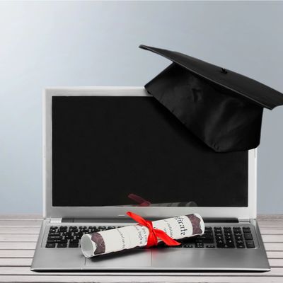 Graduation cap and diploma on a laptop symbolizing online education.