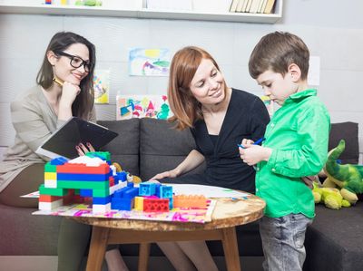 Therapist observes a parent and child. Parent is interacting with the child playing with blocks