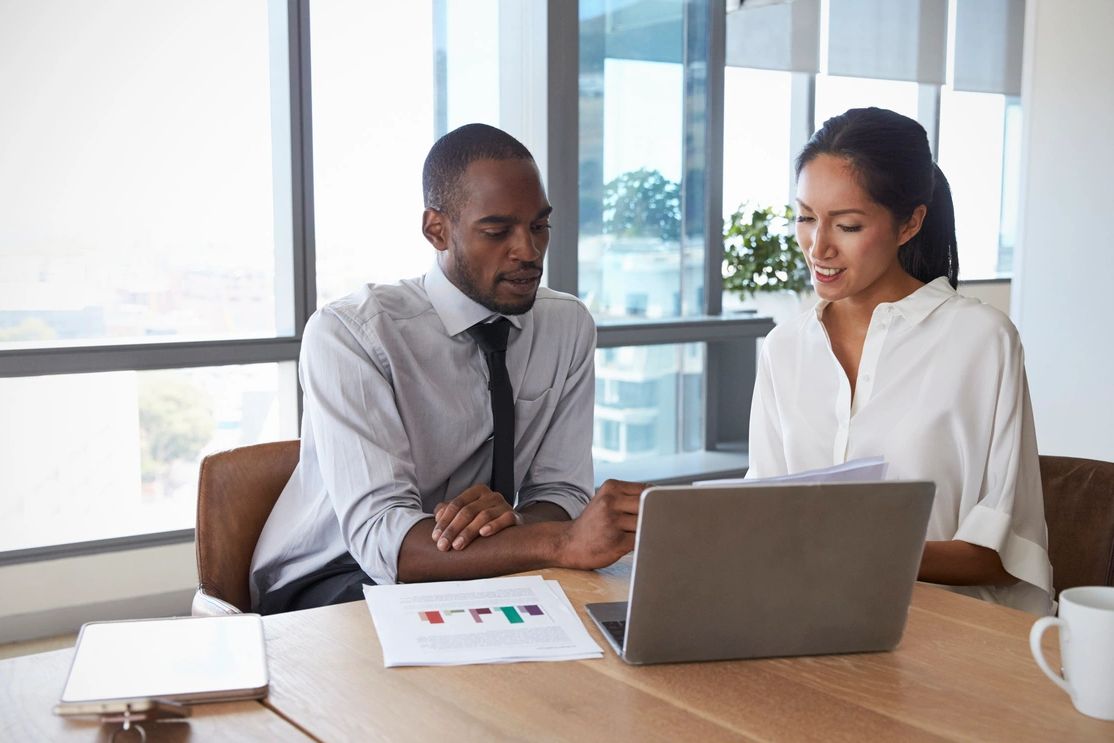 Two colleagues discussing documents in a modern office setting.