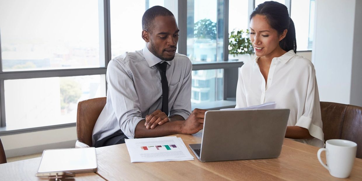 
"Insurance professionals discussing policy details over a laptop at Abrams Insurance office."