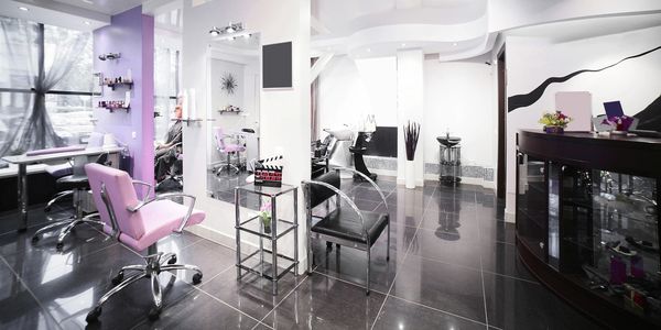 Modern beauty salon with pink and black chairs and sleek decor.