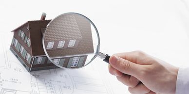 Hand holding a magnifying glass on a miniature home