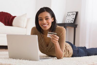 Woman holding a credit card with her laptop in front of her