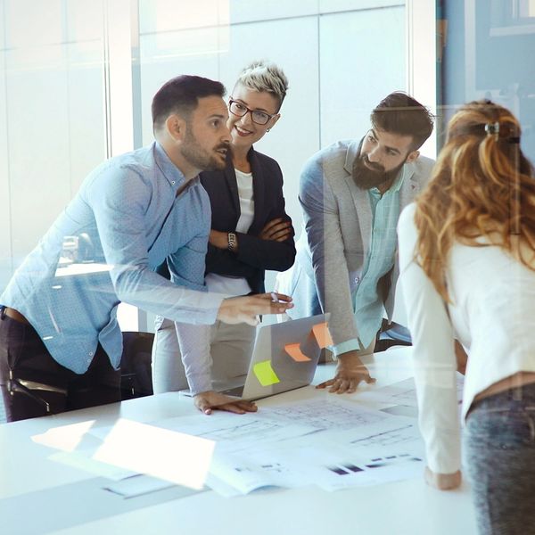 A group of professionals discussing plans around a table in a modern office.