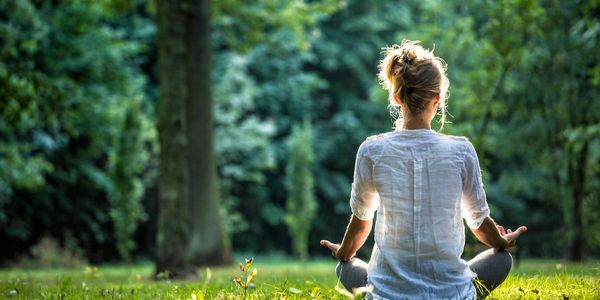 Lady sat in her meditation pose in the Sunkist Forrest taking time to relax and reconnect.