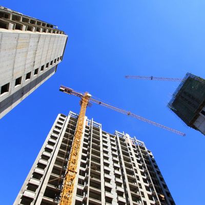 Construction cranes and tall buildings under a clear blue sky.