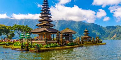 Traditional Balinese temple on a serene lake with mountains in the background.