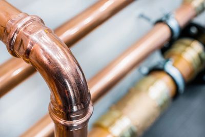 Close-up of shiny copper plumbing pipes with a bend.