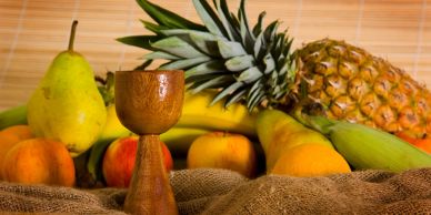 Wooden goblet with assorted fruits including pineapple and bananas.