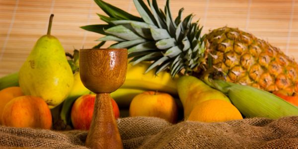 Wooden goblet with assorted fruits including pineapple and bananas.