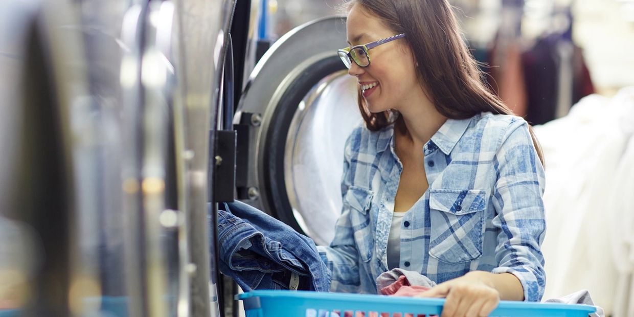 Woman putting clothes into a washer. Easy Breezy Laundromat. Laundromat near me, Coin laundry