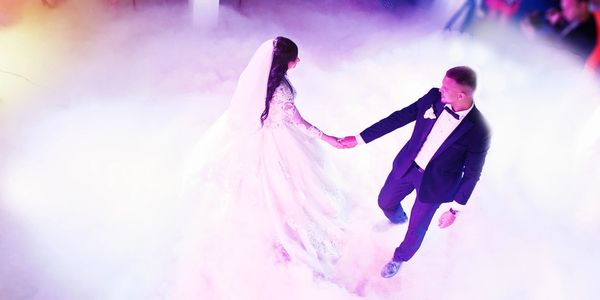 Bride and groom dancing in a foggy setting.