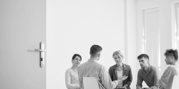 A group of people engaged in a serious discussion in a bright room.