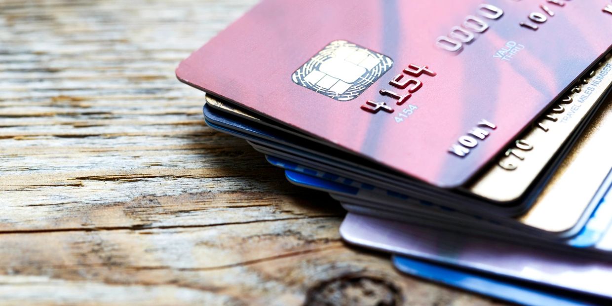 Stack of various credit cards on a wooden surface.