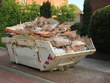 Rusty dumpster filled with construction debris on a residential street.