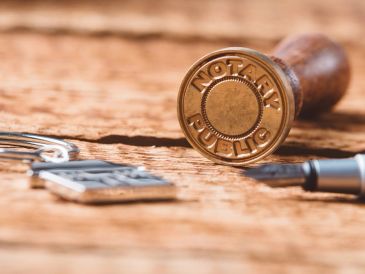 Notary public stamp and pen on wooden surface.
