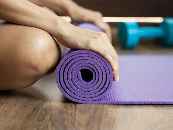 Person rolling up a Yoga mat at the end of their Yoga classes.