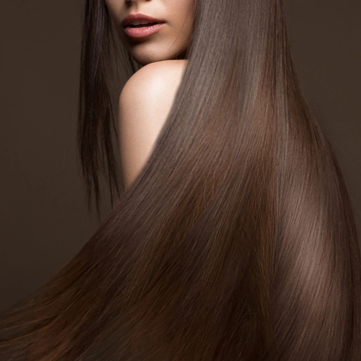 Close-up of long, smooth brown hair and a woman's lips and shoulder.