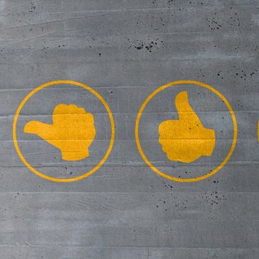Yellow thumb icons painted on gray concrete wall.