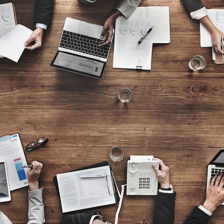 Business meeting with laptops and documents on wooden table.