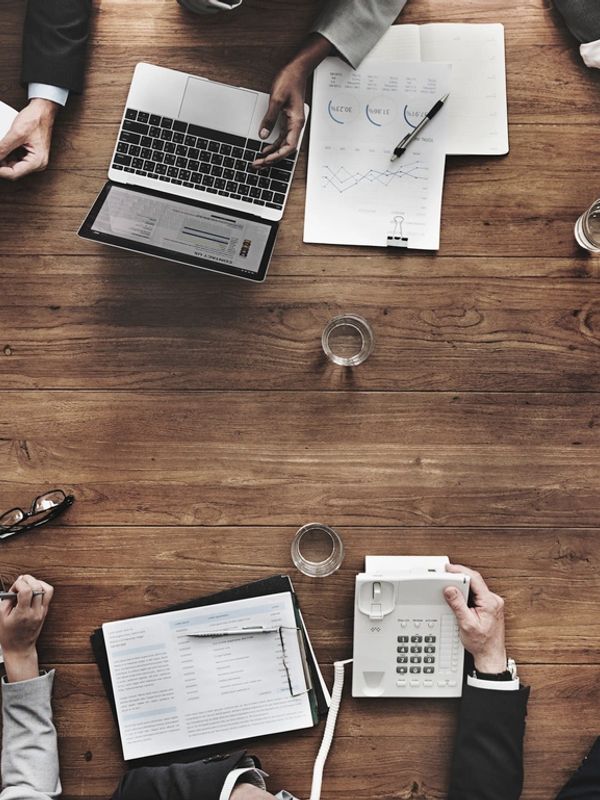 Business workers collaborating around a wooden table with documents and devices.