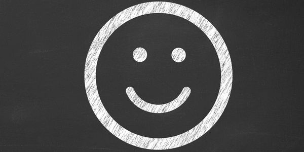 White chalk smiley face drawn on blackboard.