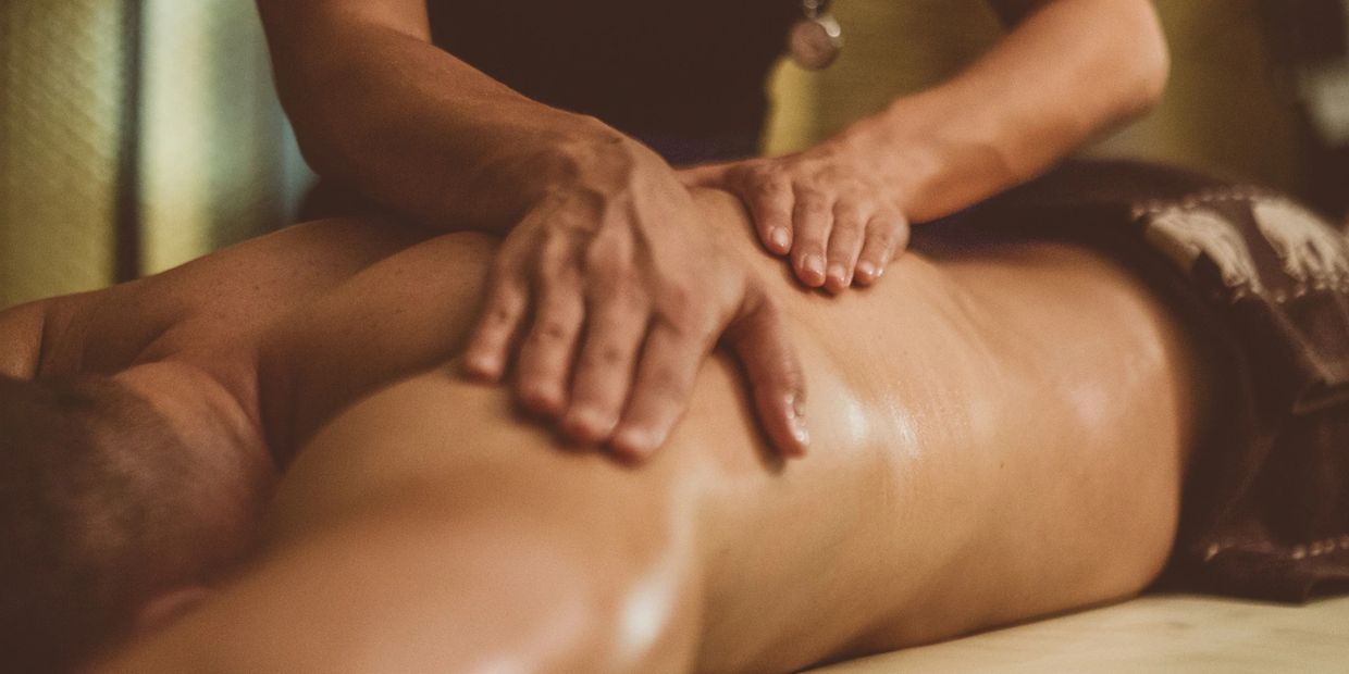 massage therapist massaging a patients shoulder blade