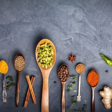 Various spices arranged in wooden spoons on a gray surface.