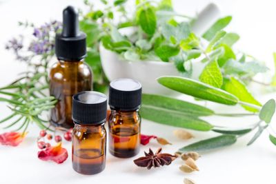 Amber glass bottles with essential oils surrounded by fresh herbs and spices.
