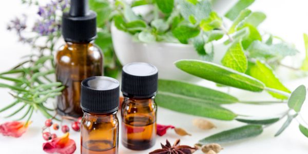 Three bottles of essential oils beside array of herbs