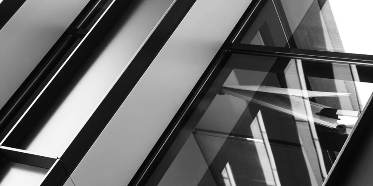 Abstract black and white architectural photo featuring glass and metal beams.