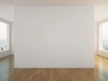 Empty white wall with wooden floor in a bright room.