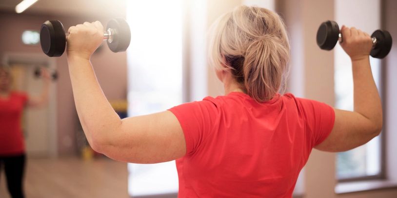 Woman exercising with dumbbells in a gym.