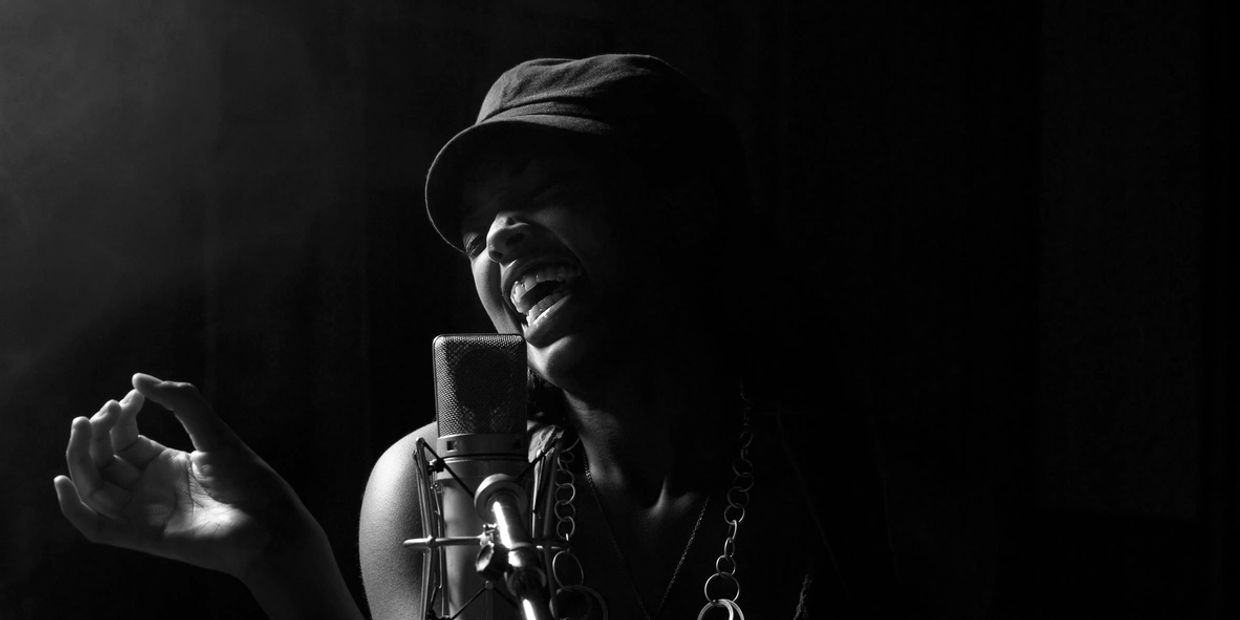 Black and white photo of a female singer passionately performing into a microphone.
