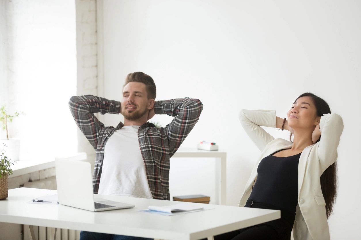 Man and a woman sitting with their hands placed behind their heads relaxing 