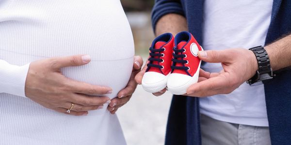 Pregnant mother and father holding baby shoes.