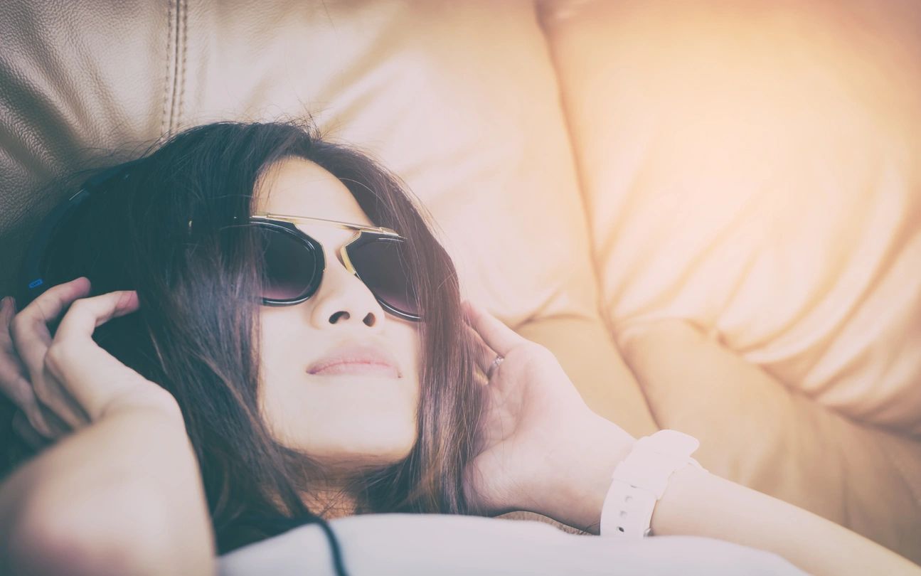 Woman laying on couch with headphones. 